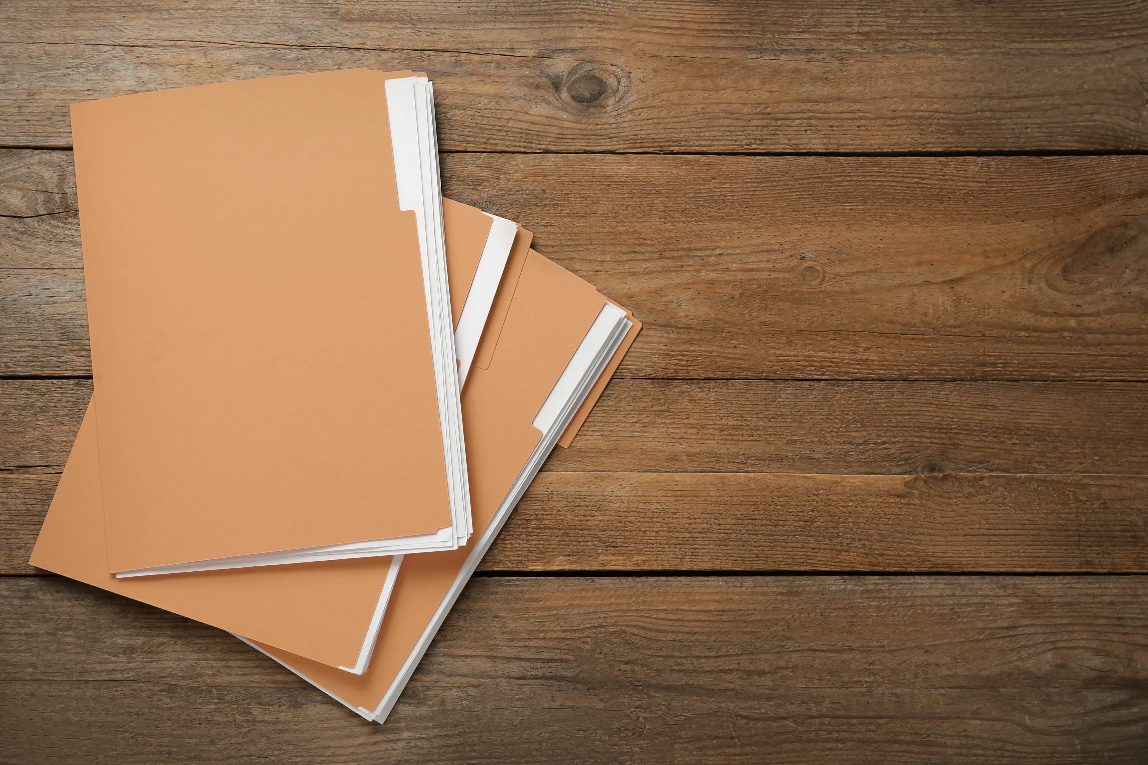 File folders containing CLUE Reports are stacked on a wooden table