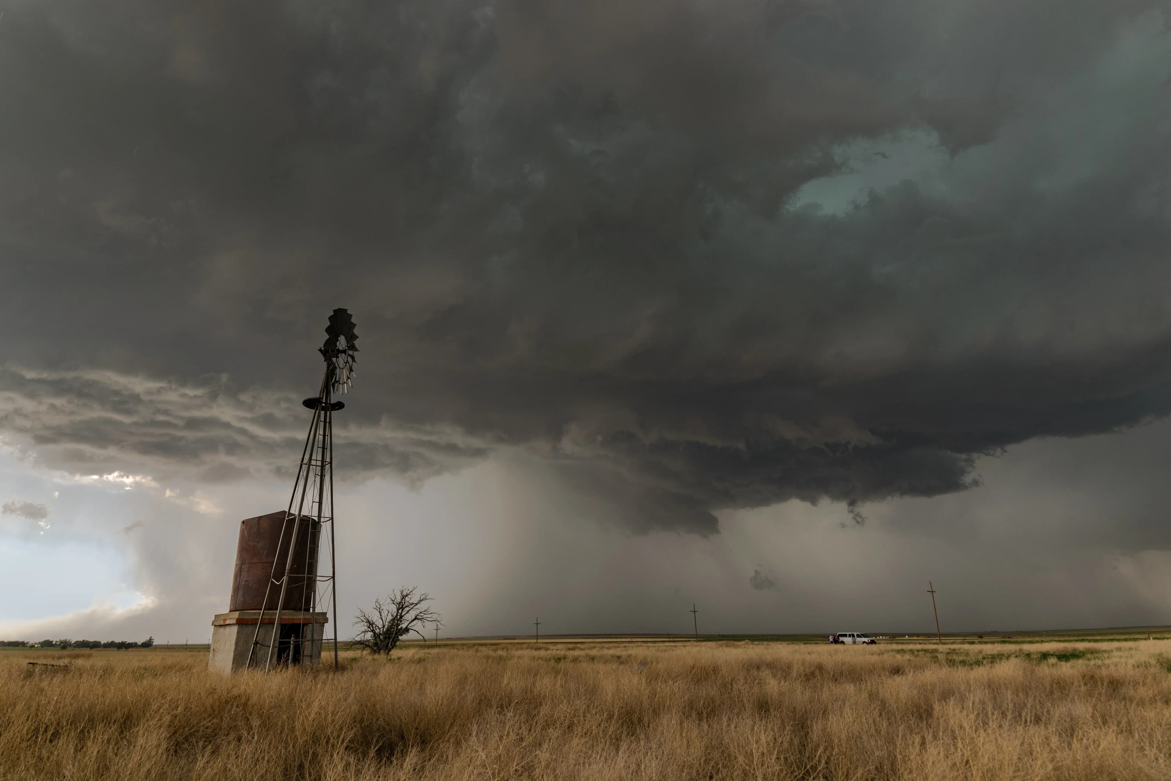 A large thunderstorm cloud producing wind and hail covers the sky above a windmill in the U.S. Great Plains
