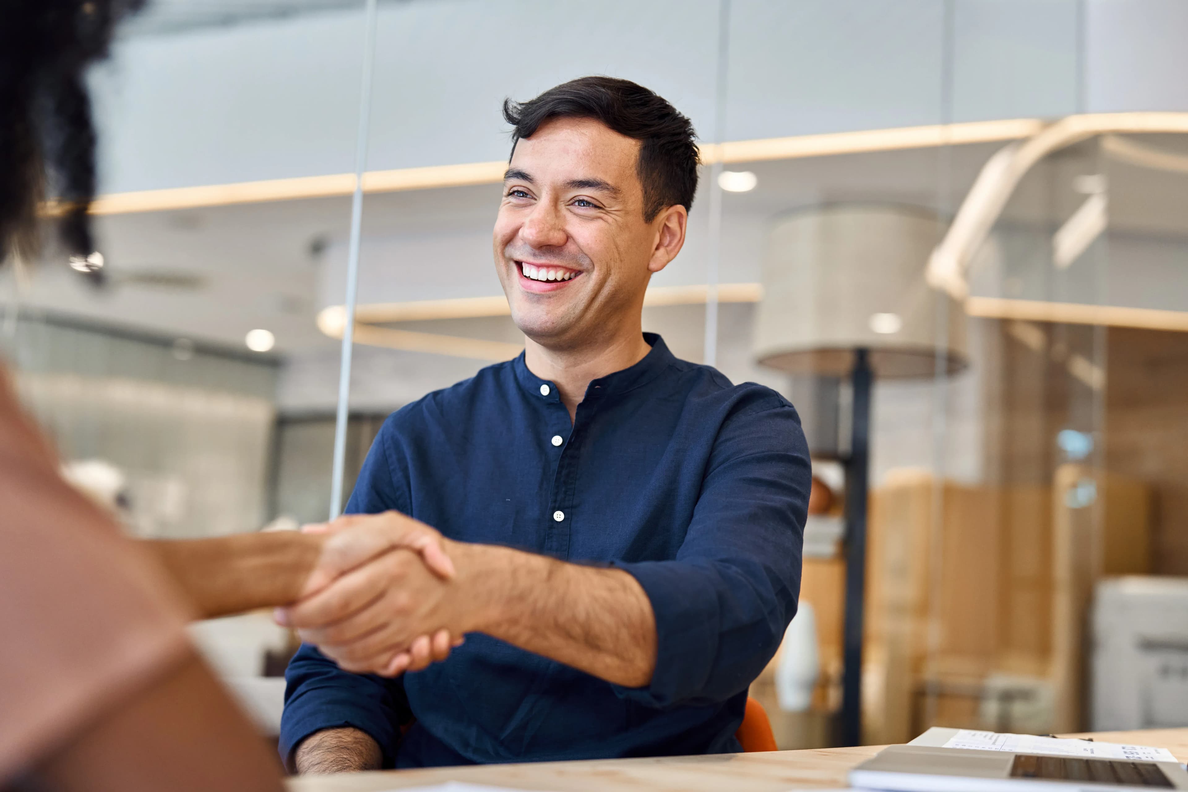 An insurance agent shakes the hand of a client after finalizing a wind and hail insurance policy