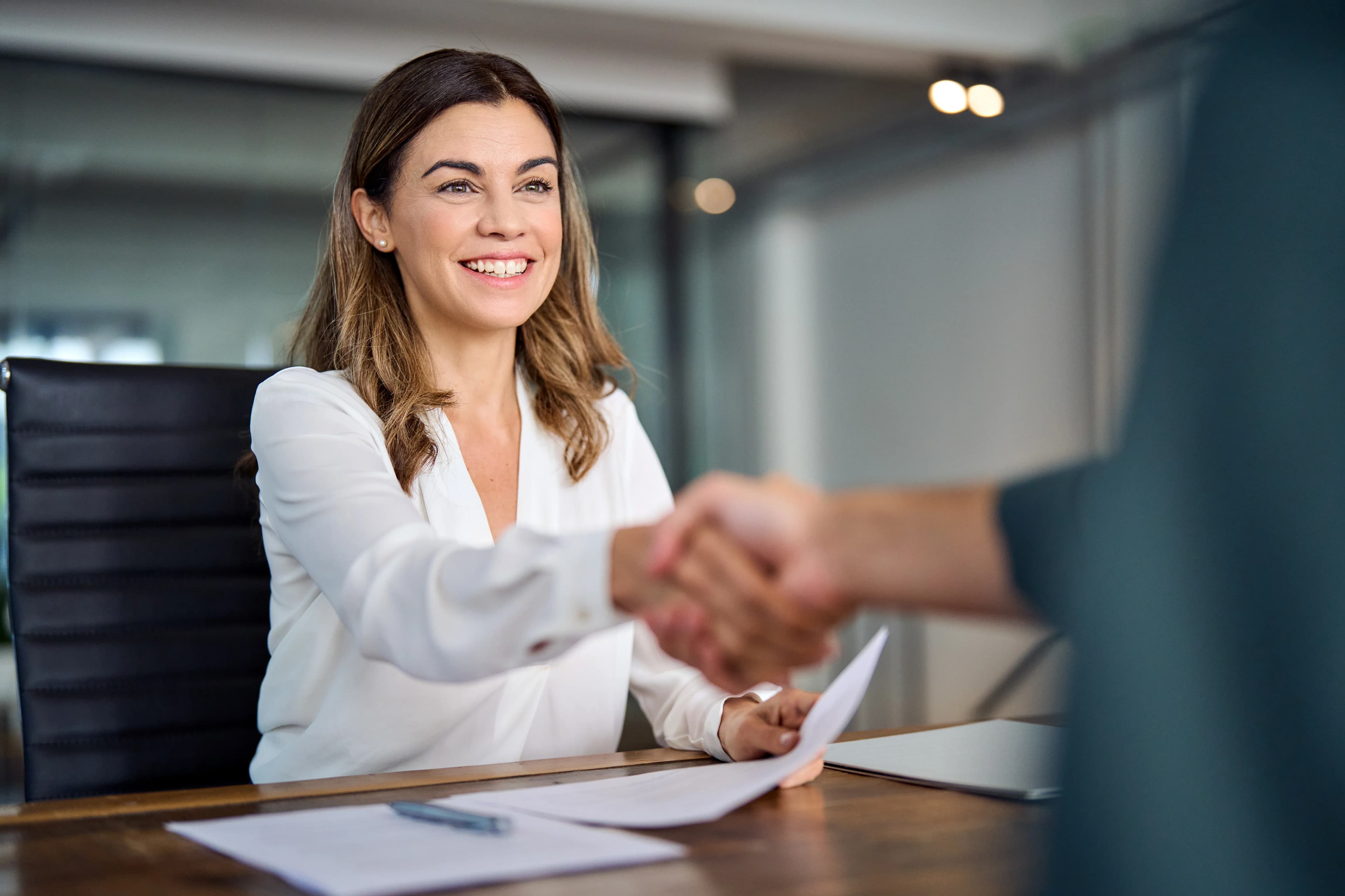 An insurance agent shakes hands with an unseen partner in agreement