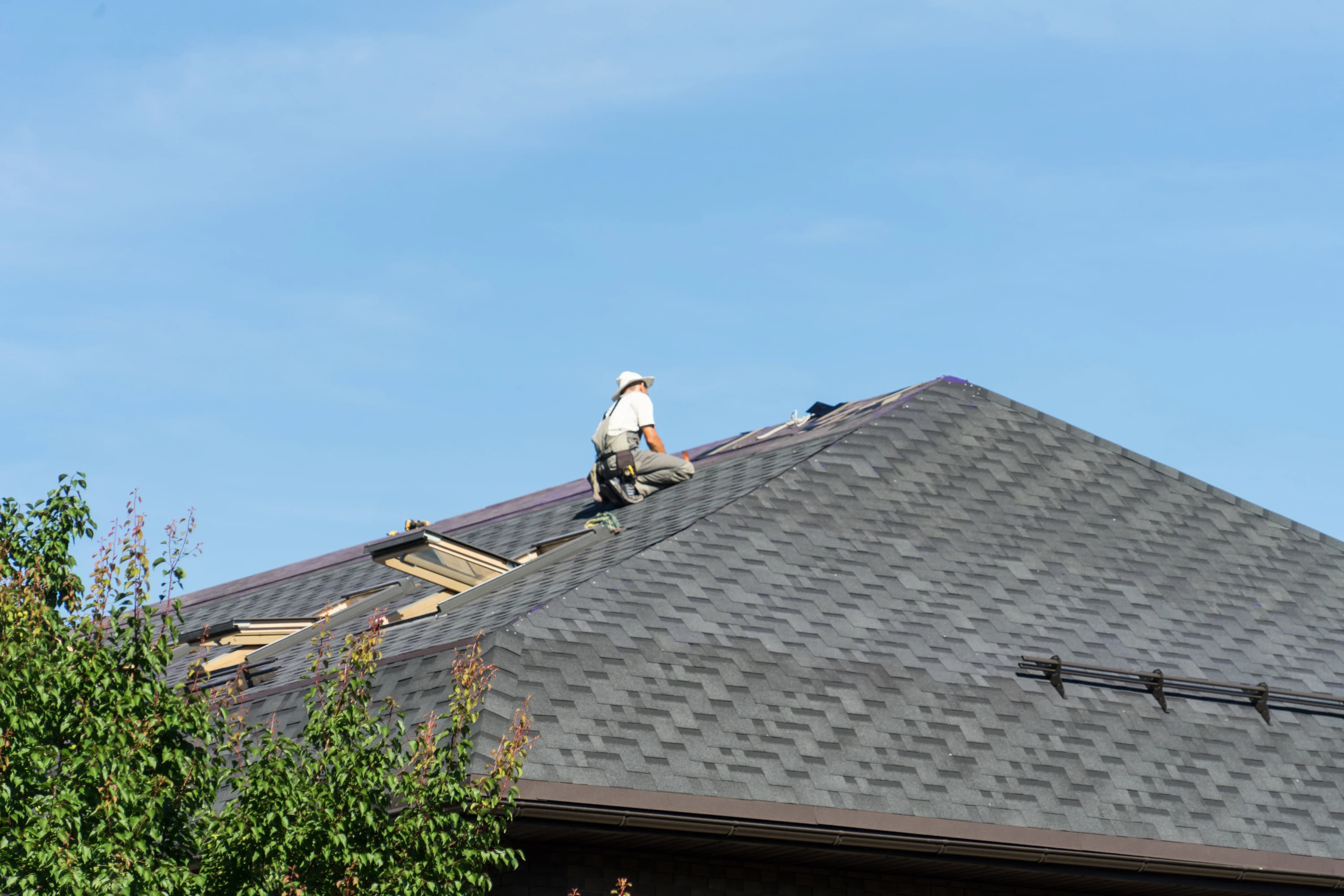 a roofer installs new shingles on the roof of a house