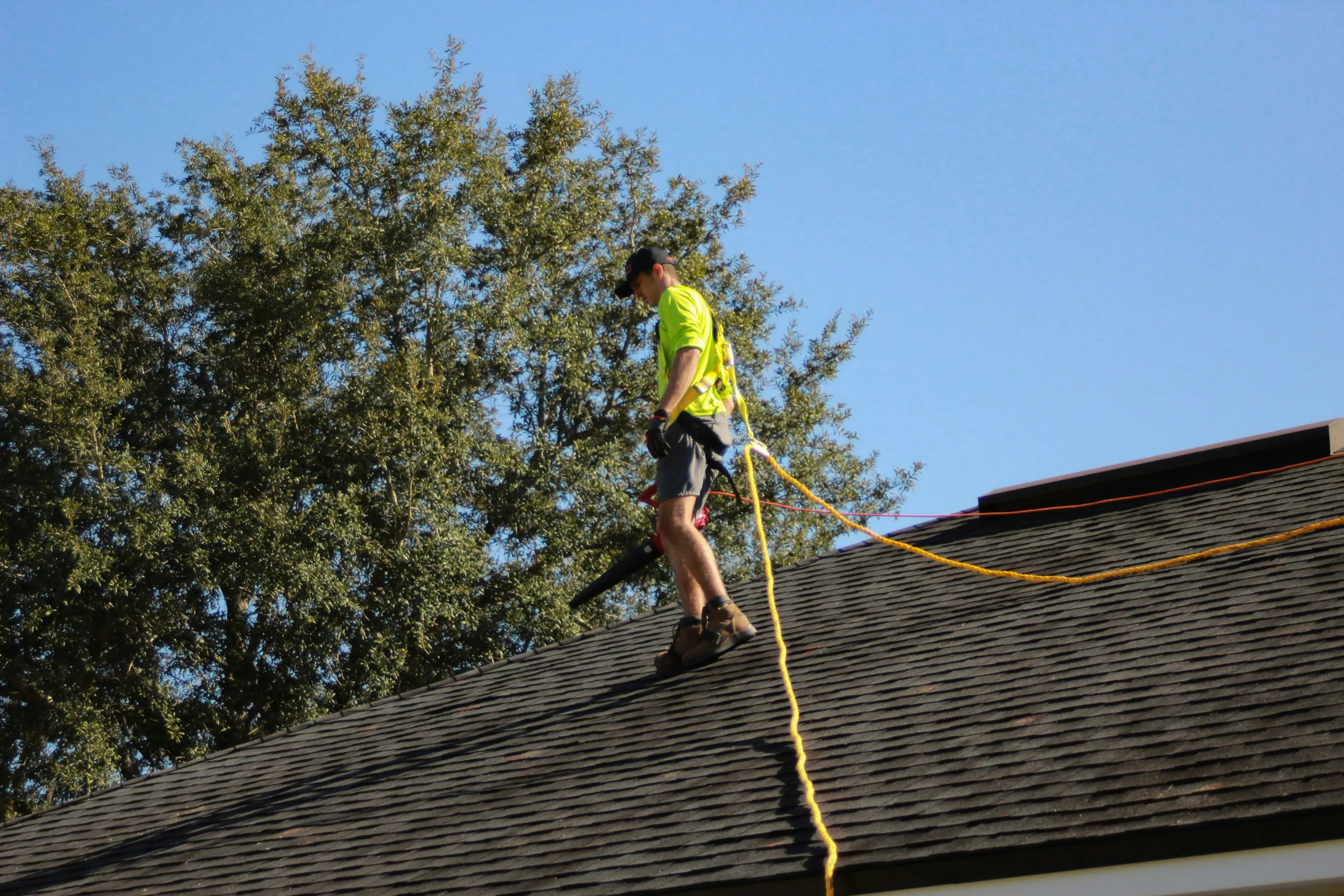 A professional roofer walks on the roof of the house, inspecting for wind or hail damage.