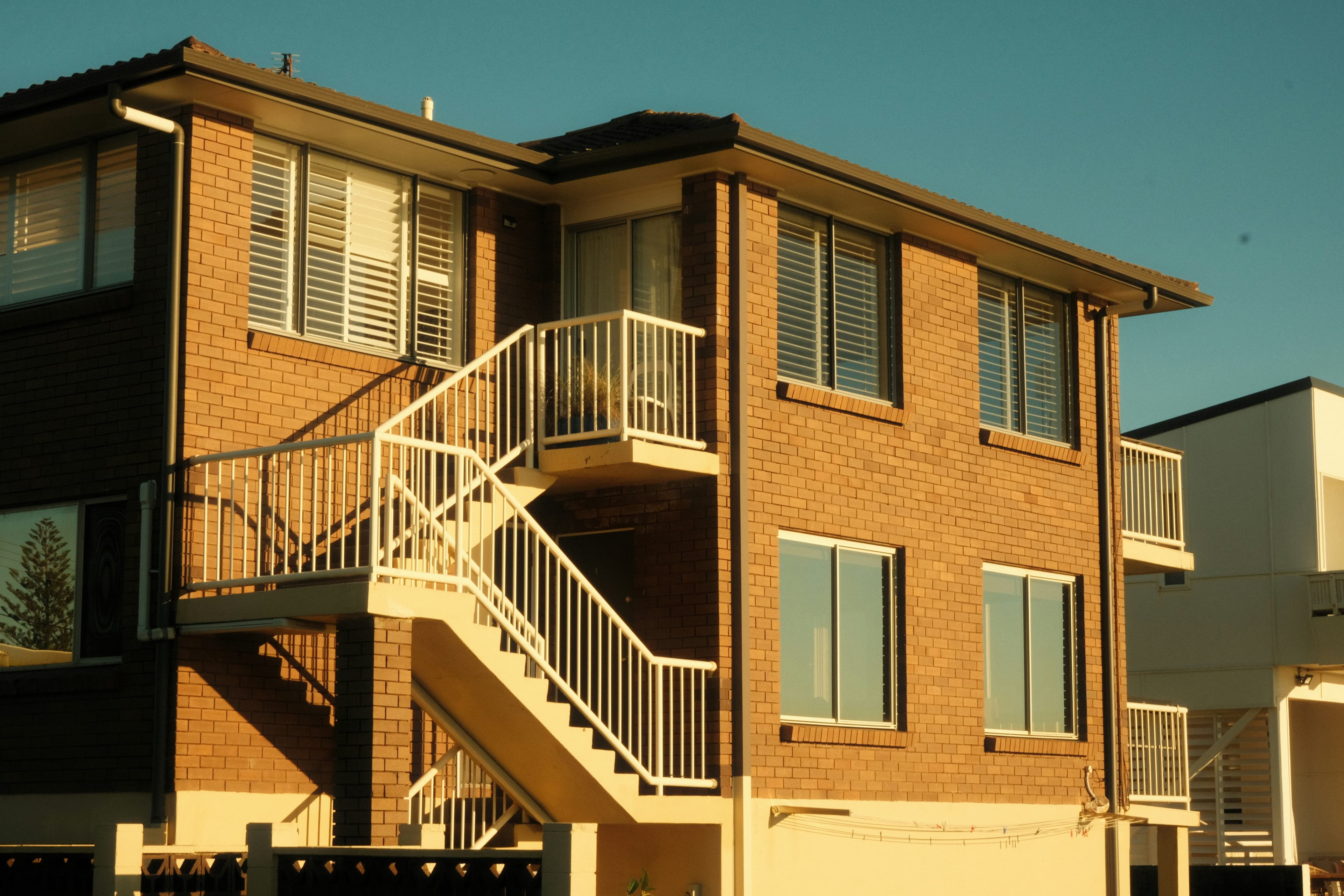 A two-story condominium home building with a white metal staircase.