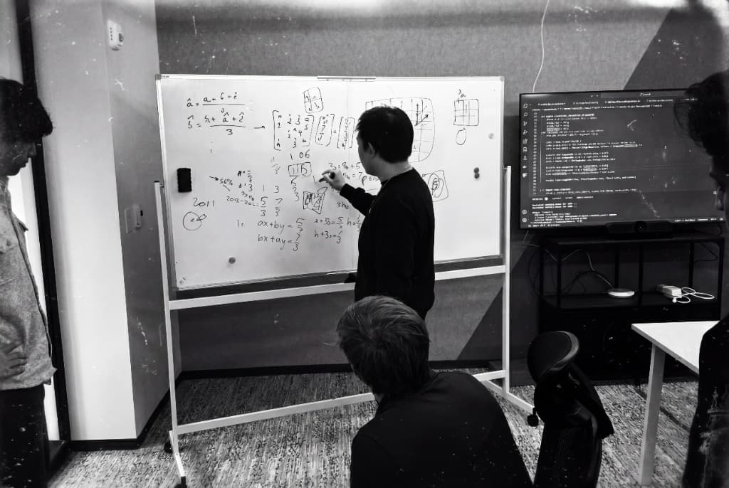 The Sola team at work, one engineer writing on a whiteboard while the others look on