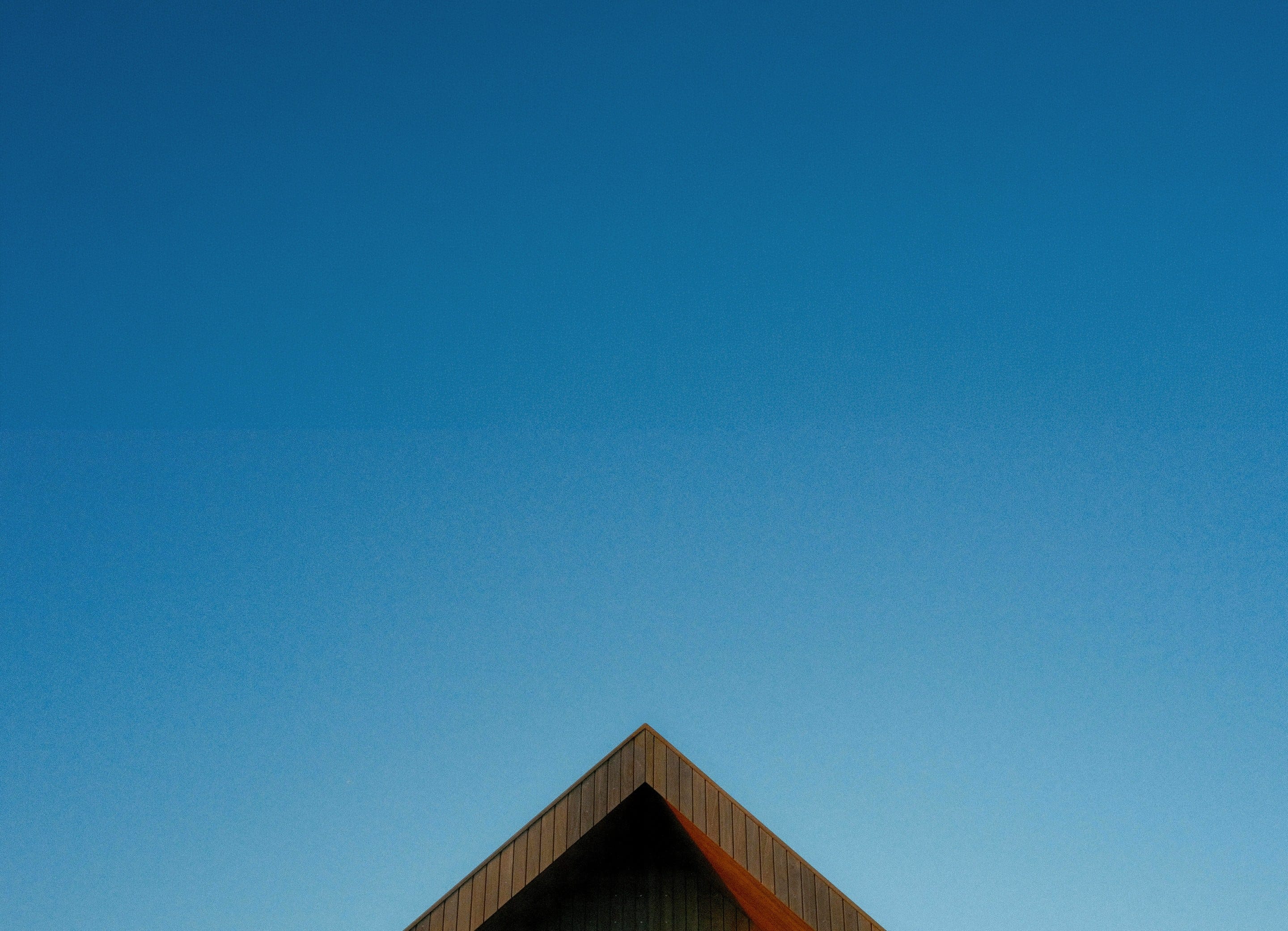 The peak of a timber gable against a clear blue sky