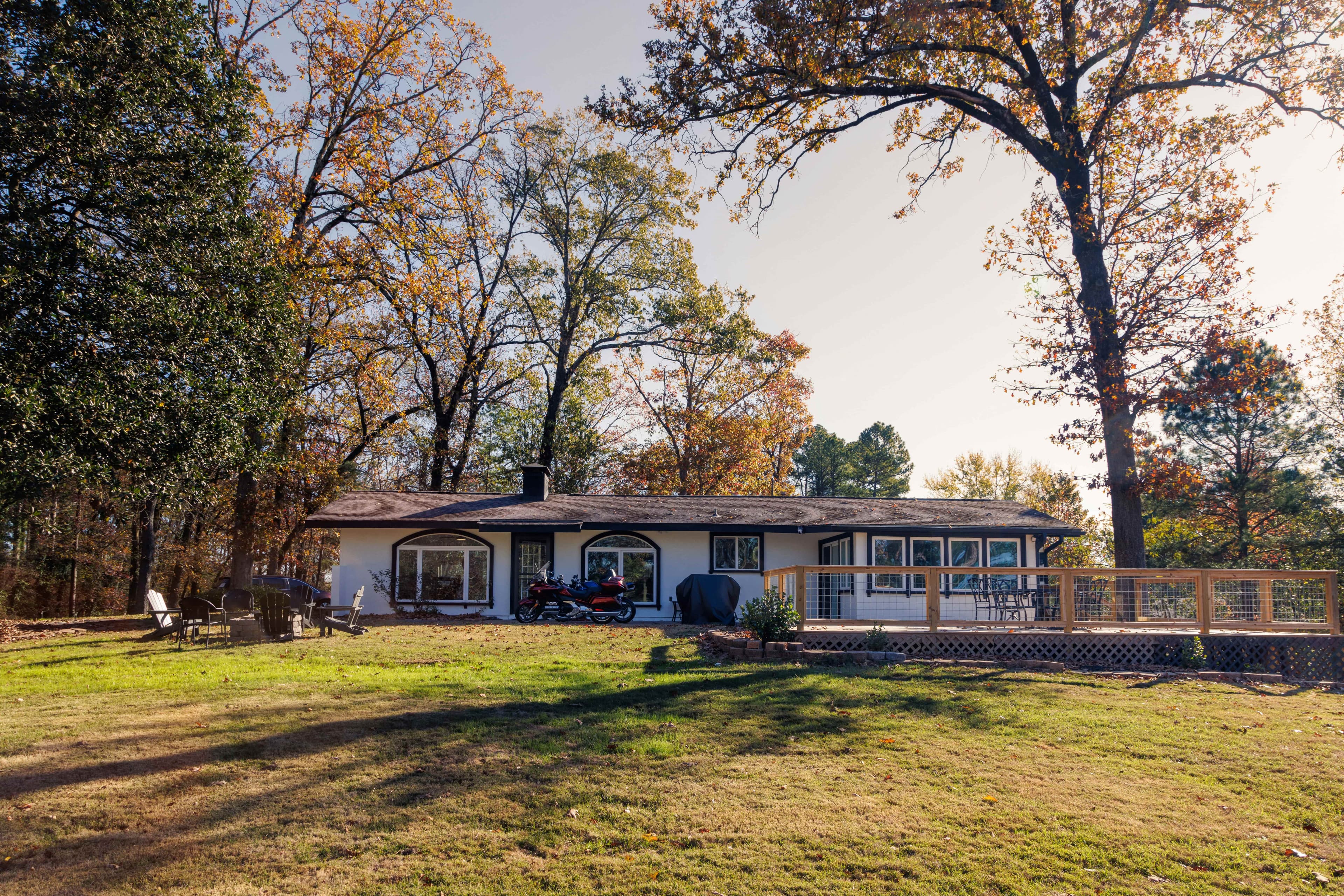 A small home in Little Rock, Arkansas sits among several tall trees on a neat green lawn.