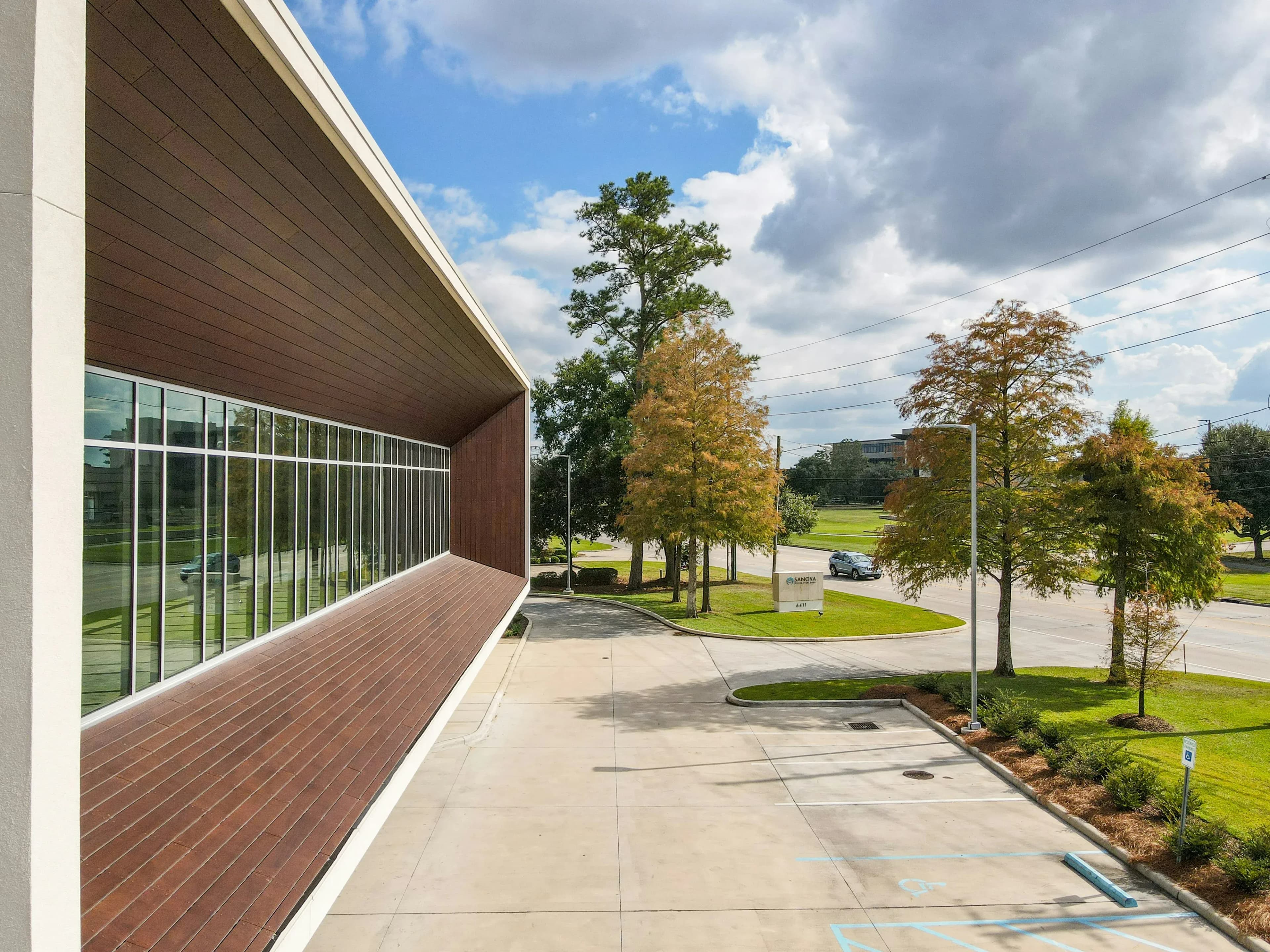 A modern office building, a type of commercial real estate, with trees outside and clouds overhead.