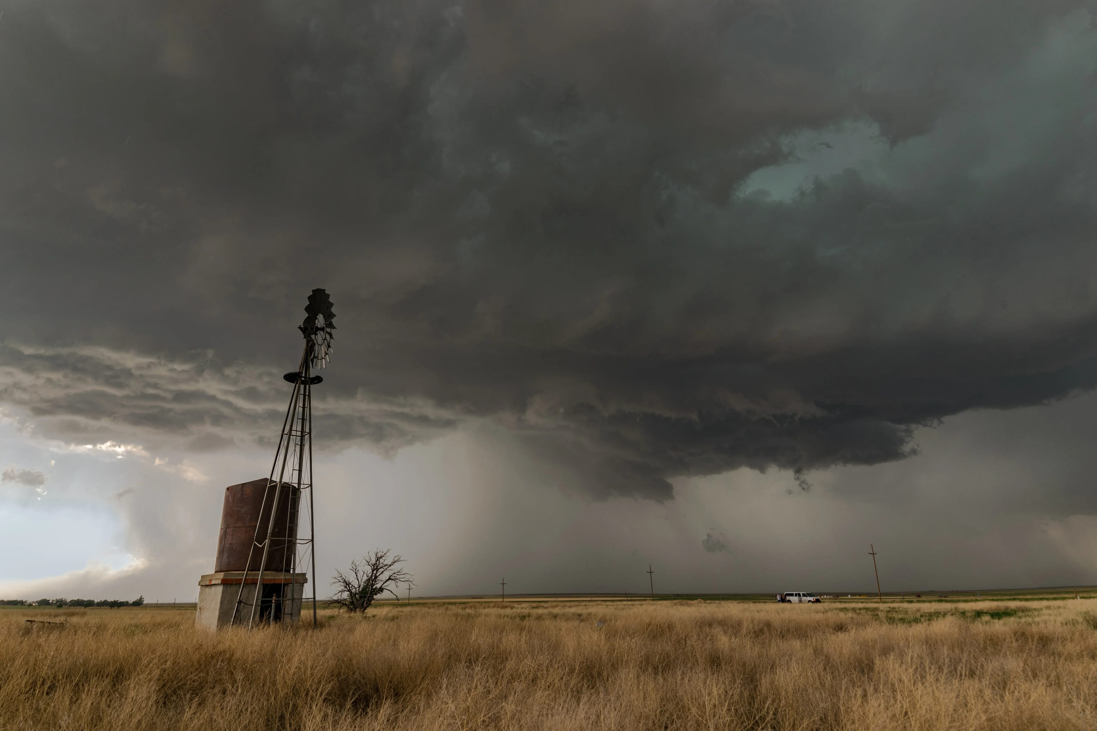 A large thunderstorm cloud producing wind and hail covers the sky above a windmill in the U.S. Great Plains