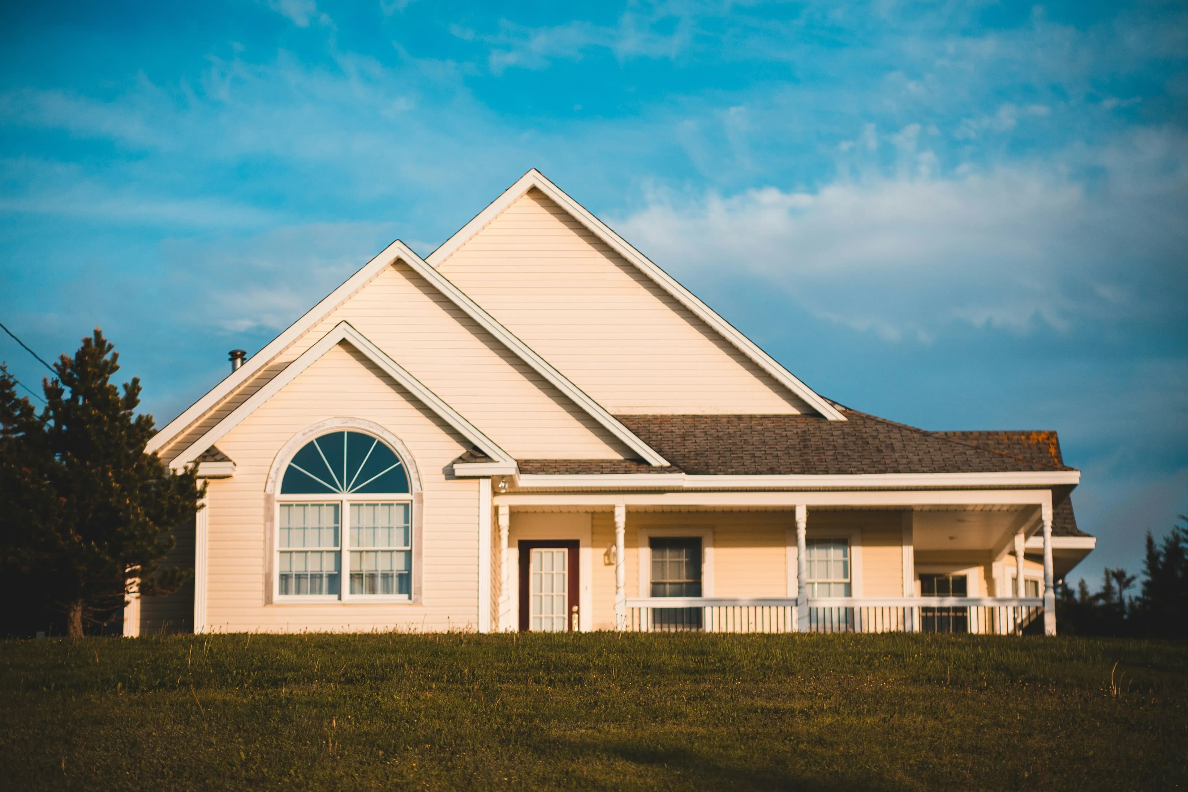 An off-white home in a midwestern state, seen under a cloudy blue sky.