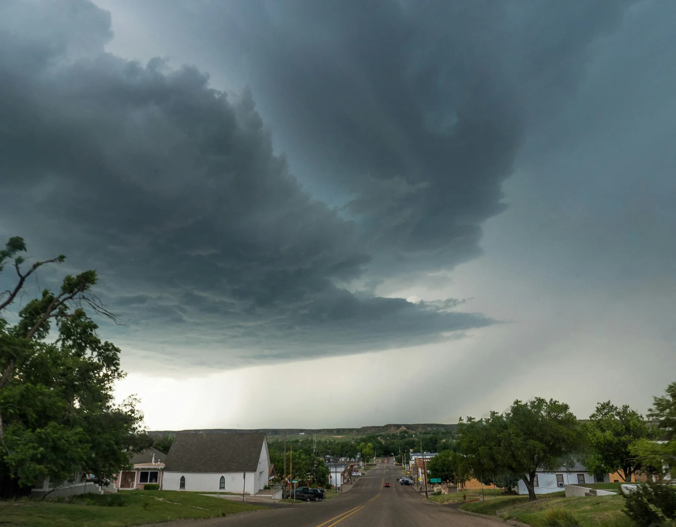 Large, dark wind storm clouds pass over a small Texas down.