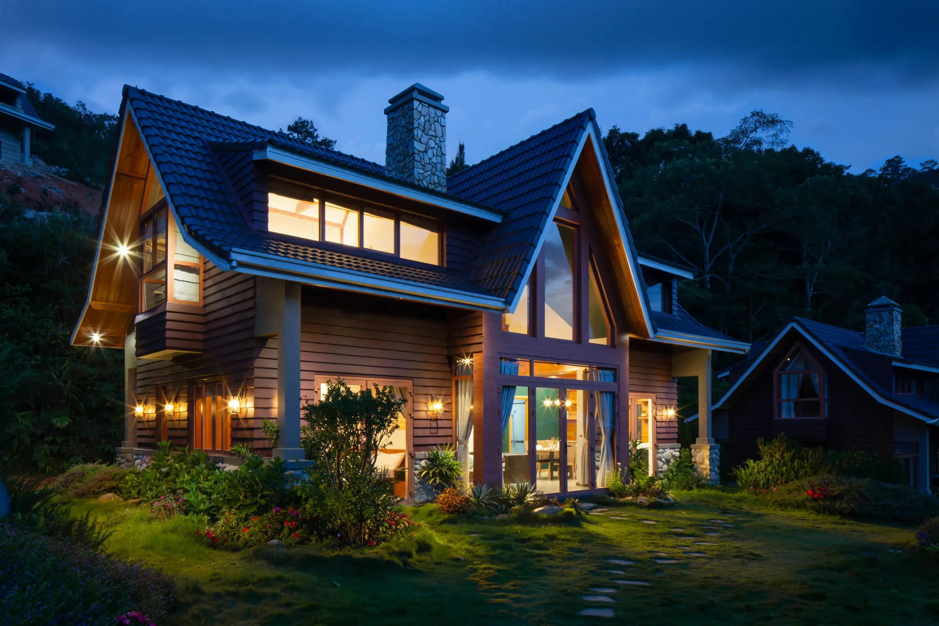 A suburban home sitting among trees, under a dusky evening sky.