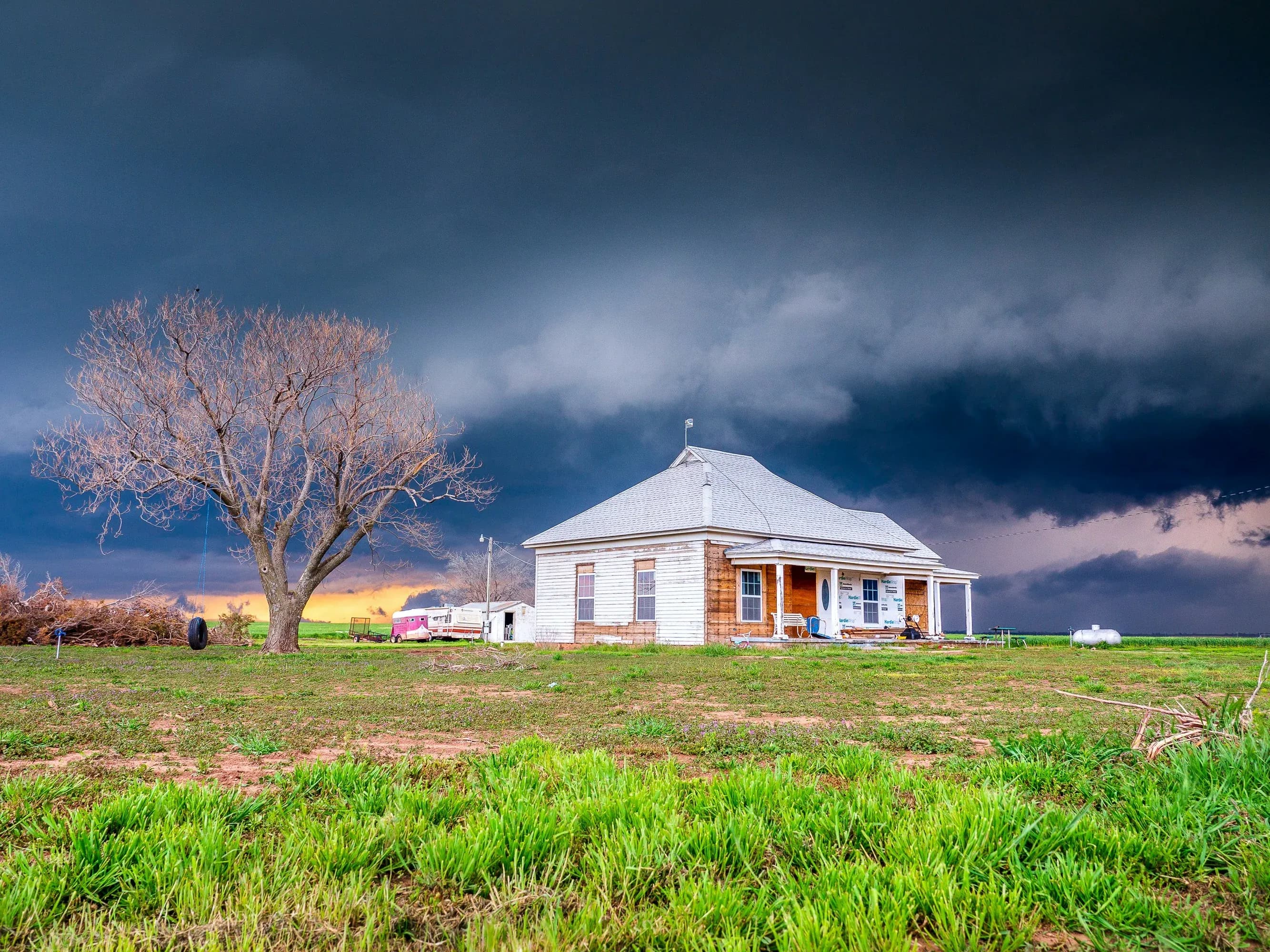 Dark clouds from thunderstorms and windstorms are seen over a small Oklahoma prairie home.